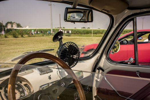 Interior of a Fiat 500 fully restored in view of a typical Italian countryside. Not just a car but an icon that created automotive history