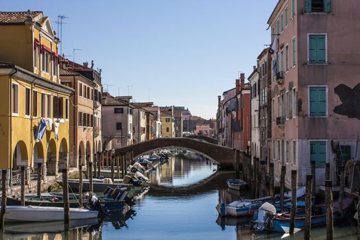 A typical landscape of Chioggia, Italian city in the Veneto lagoon near Venice. A bridge over water with half a multitude of boats of transport typical of this area ...