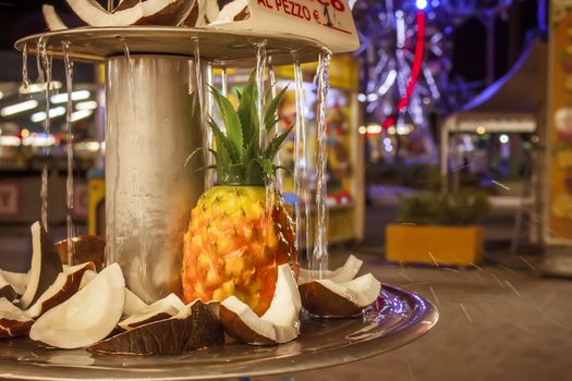 Detail of a doloci stall in a funfair Italian with coconut and pineapple rifrescati by a thin waterfall.