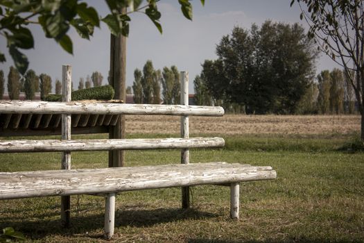 A wooden bench built by hand, immaersa in the tranquility of a typical rural landscape of northern Italy.