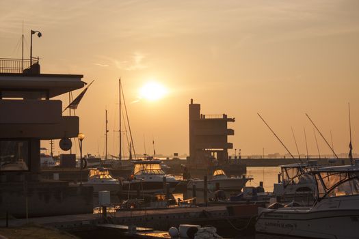 View of several boats moored on the great port of Albarella in Italy, illuminated by the warm colors of dawn