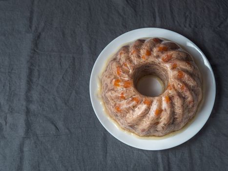 Homemade delicious jelly meat on table with dark gray linen tablecloth. Perfect jellied meat, aspic, galantine with carrot. Copy space for text. Top view or flat lay.