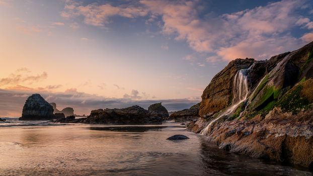 A seascape sunset with a waterfall at the beach. Humboldt County, California.