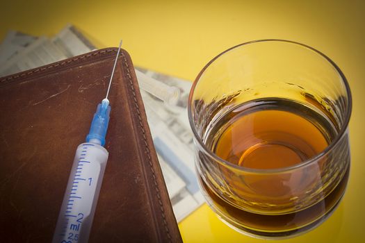 Glass with whiskey and a syringe on a glass coffee table
