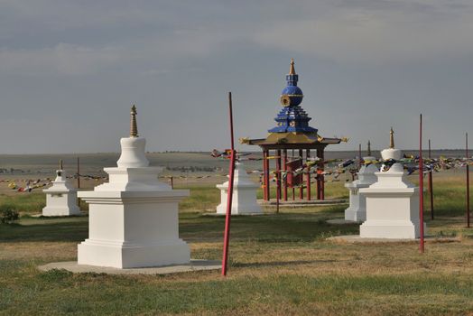 Multicolored prayer flags on the background of Buddhist stupas. Old Hurul in Kalmykia, Russia.