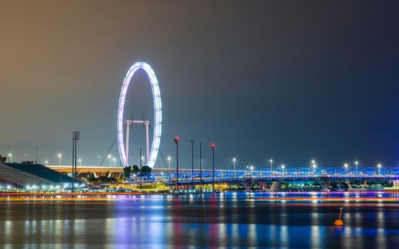 The Singapore Flyer and Helix Bridge at night, colorful lightrails created by boats.