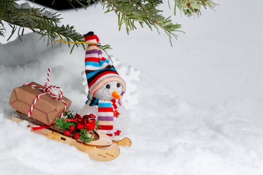 Christmas composition under the Christmas tree - a snowman, boxes with gifts on a sled, place for text copy space.