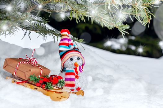 Christmas composition under the Christmas tree - a snowman, boxes with gifts on a sled, place for text copy space.