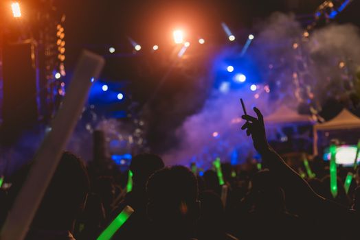 Concert crowd music festival, people raised hands on stage lights