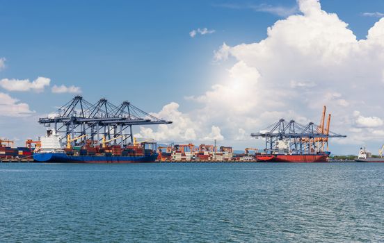 Cranes loading containers on large port cargo transport ship at day time