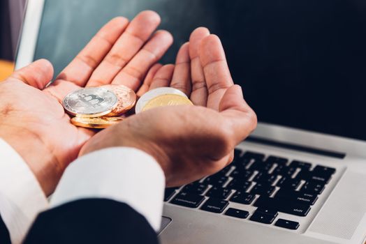 Business man holding crypto bitcoin currency money on hands with laptop computer, finance concept