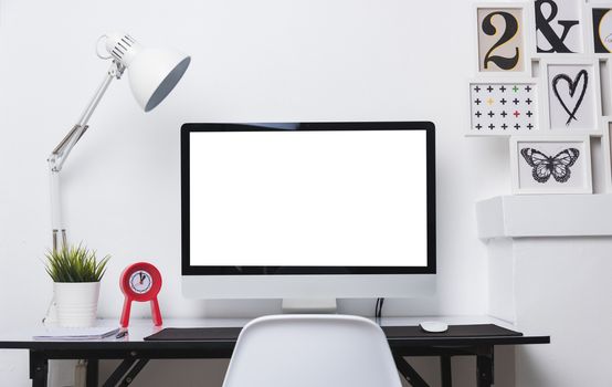Computer blank white display with work desk in office interior white wall