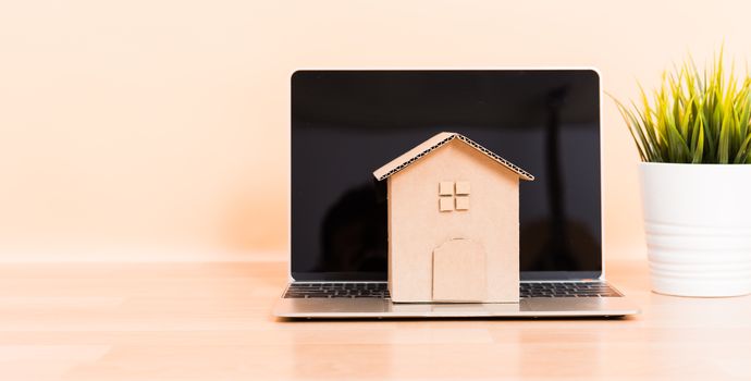 Cardboard paper model house and computer laptop, property mortgage rent buy concept