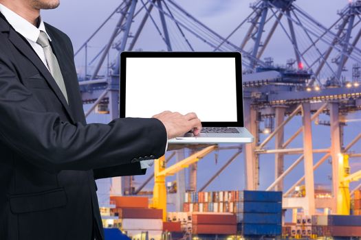 Engineering working hold conputer notebook in front of industrial harbor cargo