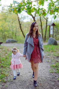 Beautiful little girl on a walk in the park on a sunny day. Autumn day