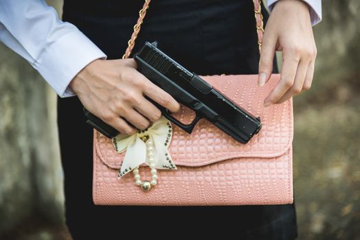 Young woman with concealed weapon gun in her small handbag