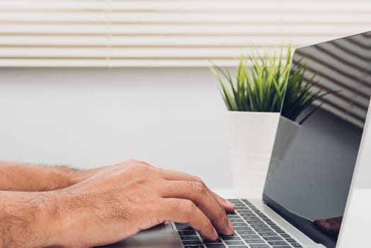 Hands of male businessmen Using keyboard on laptop computer in home office