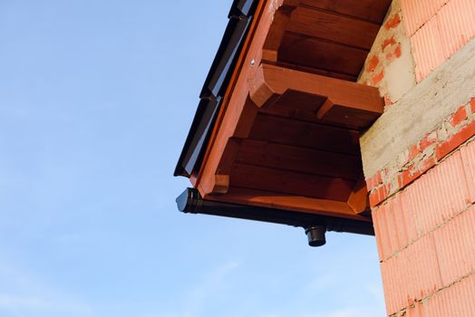 Exterior of a Unfinished Red Brick House Walls under Construction with Roof. opy space. Blue Sky.