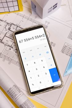 Counting the cost of building a house on a calculator .White family paper house, block of flats. Minimalistic and simple concept, style. Copy space. Vertical orientation
