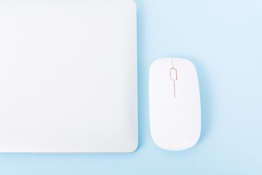 Top view close cover laptop computer notebook and wireless mouse isolated on blue background