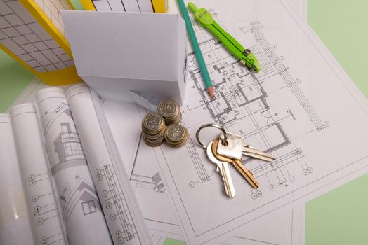 White family paper house , stack of money coins, keys, house projects plan and blueprints on mint background paper. Minimalistic and simple concept, style. Horizontal orientation