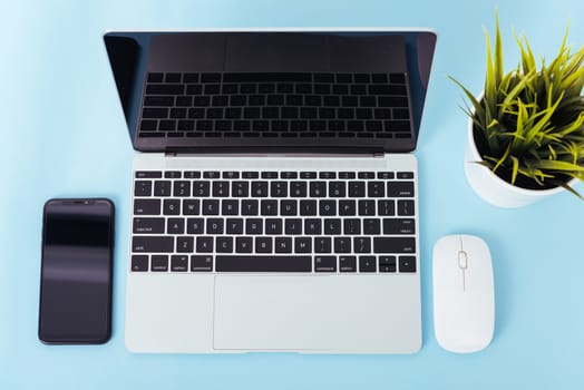 Top view of modern technology smart phone mobile and computer laptop on blue background with copy space