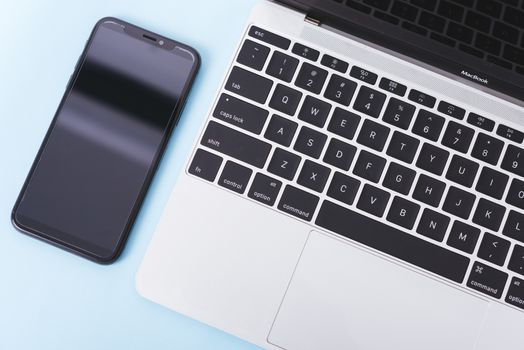 Top view of modern technology smart phone mobile and computer laptop on blue background with copy space