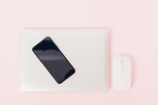 Top view of modern technology smart phone mobile and computer laptop close cover on pink background with copy space