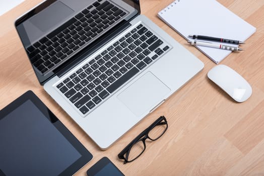 Top view open laptop with digital tablet and white smartphone on wooden desk