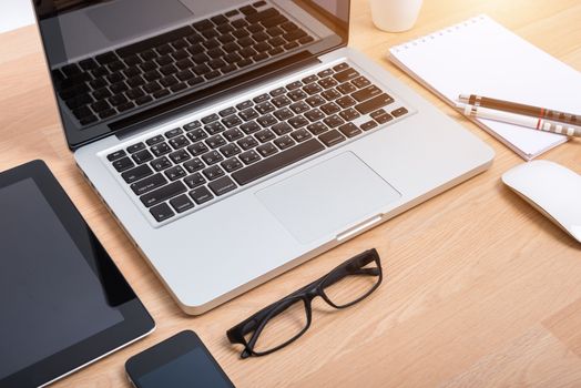 Top view open laptop with digital tablet and white smartphone on wooden desk