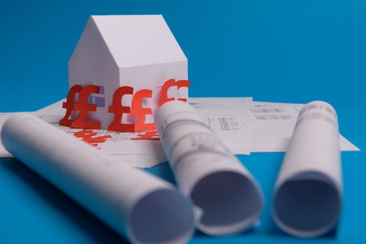 White family paper house , british pound money symbol , house projects plan and blueprints on mint background paper. Minimalistic and simple concept, style. Horizontal orientation. View from above