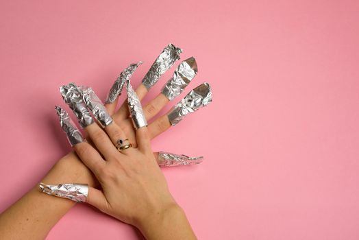 The procedure for removing varnish from nails hybrid nails in progress. Gel nail polish remover foils on woman's hands