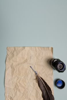Raven feather, inkwell and old yellowed paper on red background. Copy space. Old letter.