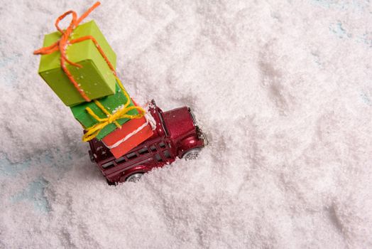 a toy car carries presents under the Christmas tree at snow. view from above. copy space