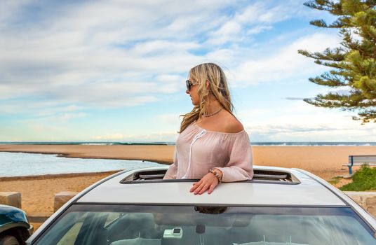 Road trip summer beach vibes. Woman stand in the sunroof of her car by the beach. travel, transport, vacation, road trip, carefree