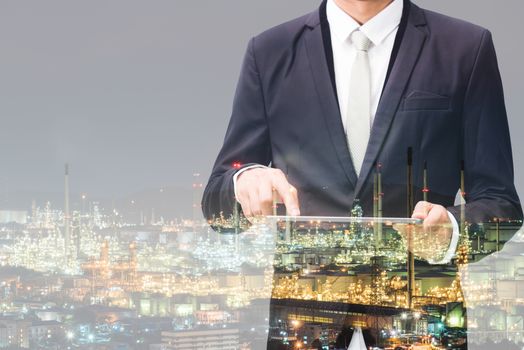 Double exposure of businessman hand hold tablet, oil refinery industry plant, Petroleum energy concept