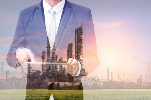 Double exposure with businessman touch on tablet and oil refinery industry plant, Petroleum