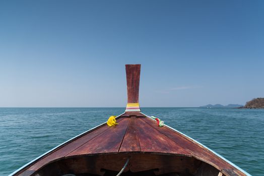 Thai wooden head longtail boat heads toward the tropical Andaman shores at Thailand andaman