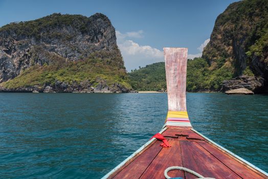 Thai wooden head longtail boat heads toward the tropical Andaman shores at Thailand andaman