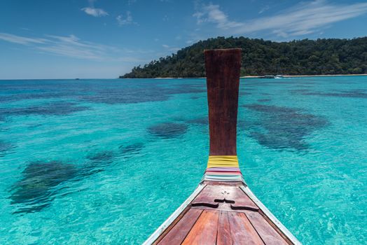 Thai wooden head longtail boat heads toward the tropical Andaman shores at Thailand andaman