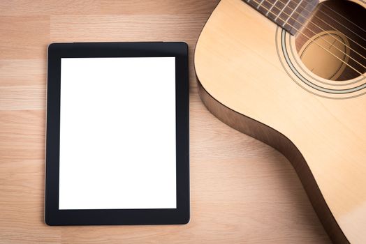Acoustic guitar with digital tablet on the wooden table