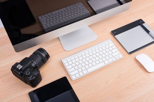 DSLR digital camera with tablet and computer PC on wooden dask table