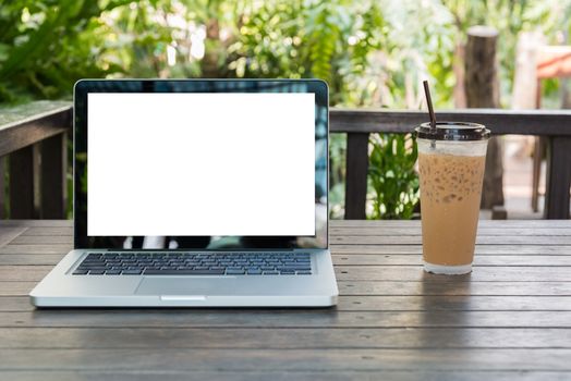 Laptop Notebook with iced coffee cup on wooden table in coffee shop and garden background