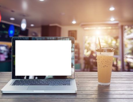 Laptop Notebook with iced coffee cup on wooden table in coffee shop
