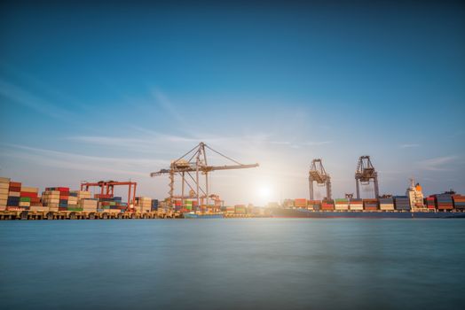 Cargo ship at Trade Port harbor with crane and blue sky over sea at sunrise