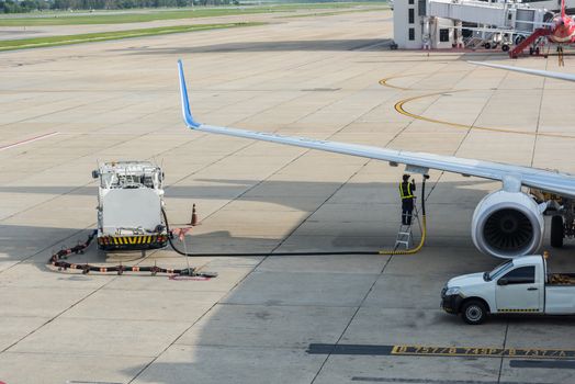 Airport man worker service refuelling the aircraft, runway