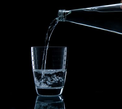 Pouring water on glass on over black background