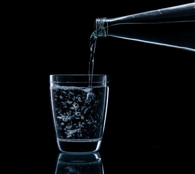 Pouring water on glass on over black background