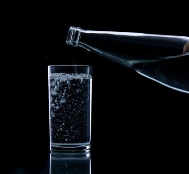 Pouring water on glass on over black background