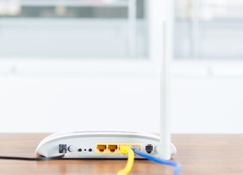 Wireless modem router network hub with cable connect on wooden table in the room